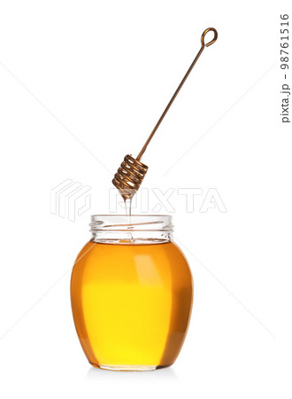 Honey dripping from dipper into jar isolated on white Honey dripping from dipper into jar isolated on white 98761516