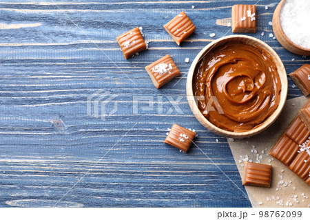 Salted caramel on blue wooden table, flat lay. Space for text 98762099