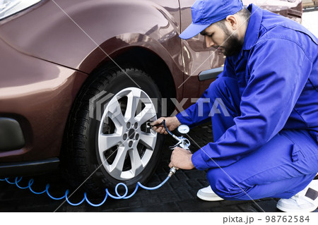 Mechanic checking tire air pressure at car service Mechanic checking tire air pressure at car service 98762584