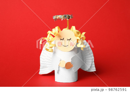 Toy angel made of toilet paper hub on red background 98762591