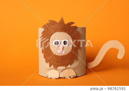 Toy lion made of toilet paper roll on orange background 98762592