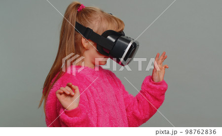 Preteen child girl kid using headset app to play simulation game watching virtual reality 3D video 98762836