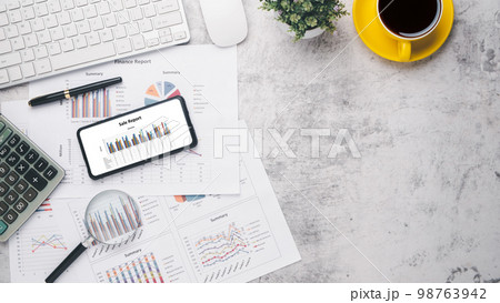 Smart phone with charts and reports on office desk workplace. Top view flat lay Smart phone with charts and reports on office desk workplace. Top view flat lay 98763942