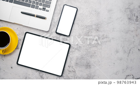 Office desk workplace with blank screen tablet and smart phone, laptop, pen and cup of coffee, Top view flat lay with copy space. 98763943