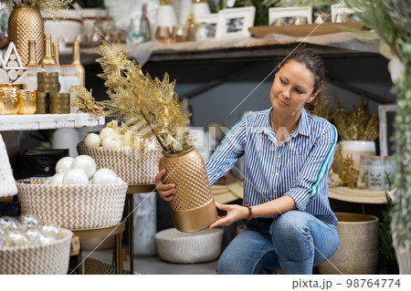 Woman choosing decorative plant in christmas store Woman choosing decorative plant in christmas store 98764774