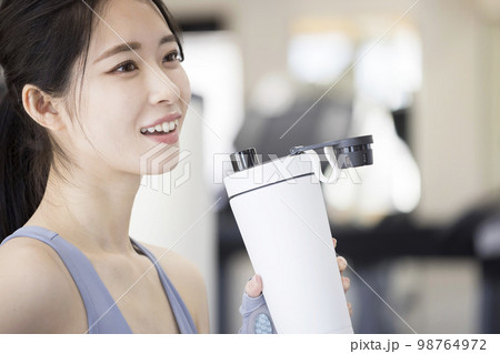 スポーツジムでトレーニング後プロテインを飲む若い女性 98764972