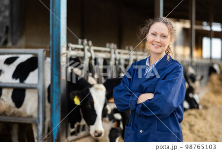 Positive woman farmer in cowshed Positive woman farmer in cowshed 98765103