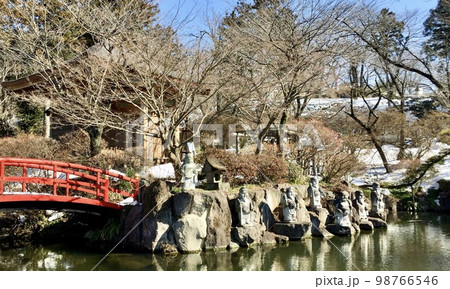 池のほとりの七福神と赤い橋と残雪 98766546
