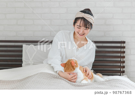 家のベッドルーム・寝室で猫・ペットを可愛がる飼い主の女性(話しかける) 家のベッドルーム・寝室で猫・ペットを可愛がる飼い主の女性(話しかける) 98767368