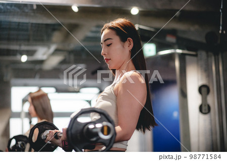 ジムで腕を鍛える女性 98771584