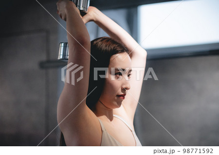 ジムで腕を鍛える女性 98771592