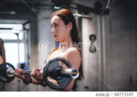 ジムで腕を鍛える女性 98771597