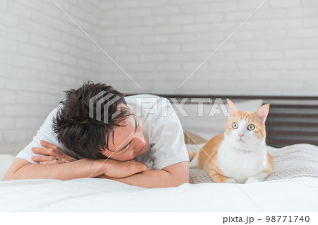 家のベッドルーム・寝室でくつろぐ猫と飼い主の男性(リラックス) 家のベッドルーム・寝室でくつろぐ猫と飼い主の男性(リラックス) 98771740