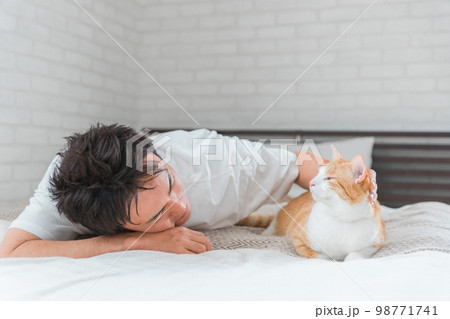 家のベッドルーム・寝室でくつろぐ猫と飼い主の男性(リラックス) 家のベッドルーム・寝室でくつろぐ猫と飼い主の男性(リラックス) 98771741