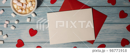 Banner Greeting or invitation card mock up with red envelope with white cup of coffee and marshmallows on wooden background. Romantic Valentine day. Blank paper card copy space for your text. Holiday 98771918