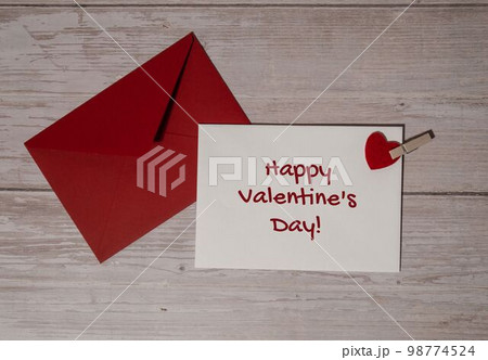 HAPPY VALENTINES DAY text Greeting card with red envelope on wooden background. Romantic Small hearts Valentine day. Holiday morning HAPPY VALENTINES DAY text Greeting card with red envelope on wooden background. Romantic Small hearts Valentine day. Holiday morning 98774524