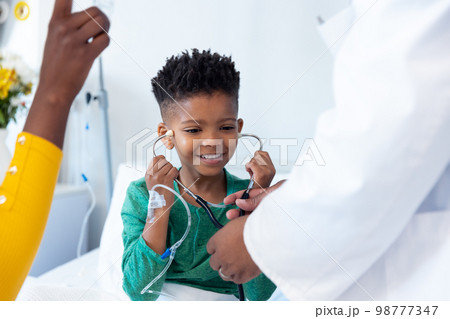 Smiling african american boy patient trying doctor's stethoscope in hospital 98777347