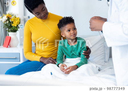 Smiling african american son patient with mother and male doctor in hospital 98777349