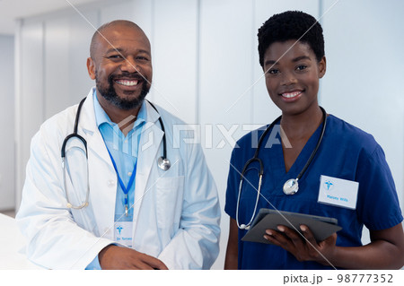 Portrait of smiling african american male and female doctor in hospital corridor 98777352