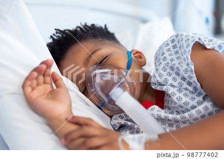 African american boy patient on ventilator asleep in hospital bed 98777402