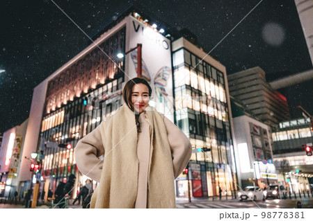 雪の降る夜の街と女性 98778381