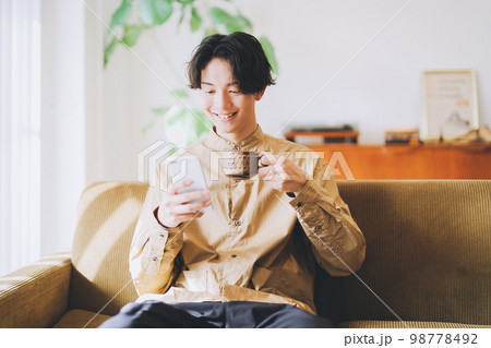 コーヒーを飲みながらスマホを見る男性 コーヒーを飲みながらスマホを見る男性 98778492