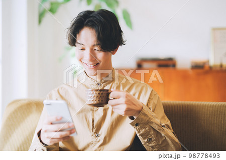 コーヒーを飲みながらスマホを見る男性 コーヒーを飲みながらスマホを見る男性 98778493