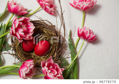 A nest with painted eggs is decorated with beautiful pink tulips A nest with painted eggs is decorated with beautiful pink tulips 98778570