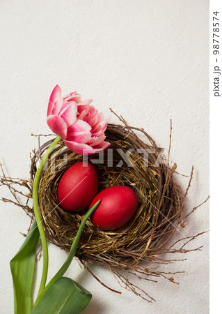 A nest with painted eggs is decorated with beautiful pink tulip A nest with painted eggs is decorated with beautiful pink tulip 98778574