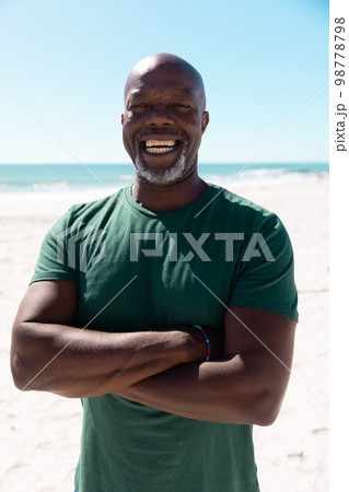 Portrait of bald african american senior man with arms crossed laughing at beach during summer Portrait of bald african american senior man with arms crossed laughing at beach during summer 98778798