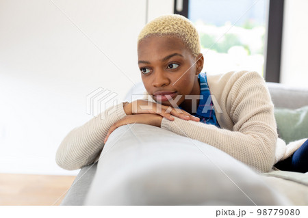 Happy african american woman sitting on sofa in living room Happy african american woman sitting on sofa in living room 98779080