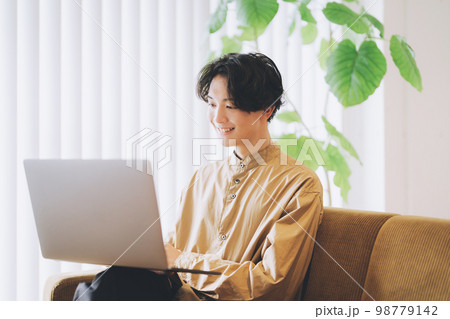 ソファでパソコンを使う男性 98779142