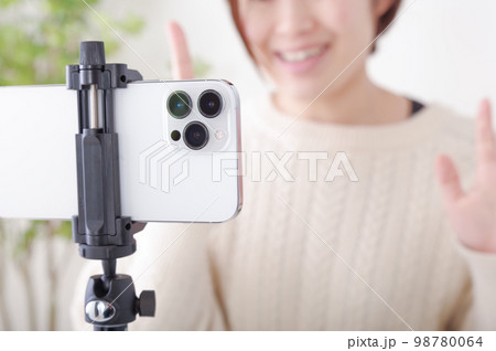 固定されたスマホに向かってしゃべる女性 固定されたスマホに向かってしゃべる女性 98780064