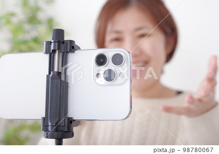 固定されたスマホに向かってしゃべる女性 固定されたスマホに向かってしゃべる女性 98780067