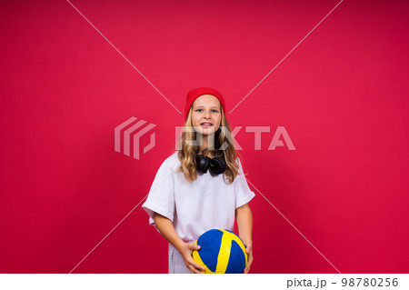 Portrait of a cute eight year old girl in volleyball outfit isolated on a red background 98780256