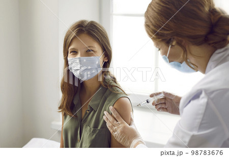 Happy teenage child in medical face mask getting vaccinated against viral infection 98783676
