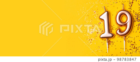 Gold candles in the form of number nineteen on yellow background with confetti. 19 years celebration. Greeting banner. 98783847