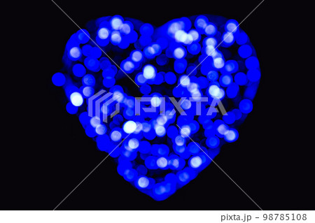 Blue and white defocused bokeh circles of light in the shape of a heart on a black backdrop 98785108