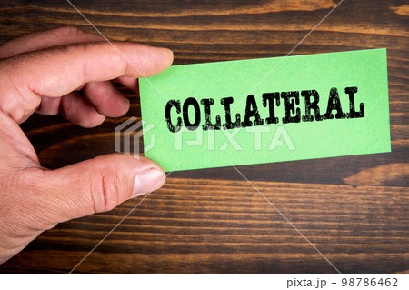 Collateral. Text on green sticky note. Wood texture background 98786462