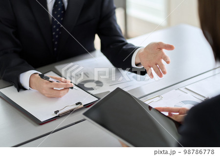 タブレットを見せて説明するアジア人ビジネスパーソン タブレットを見せて説明するアジア人ビジネスパーソン 98786778