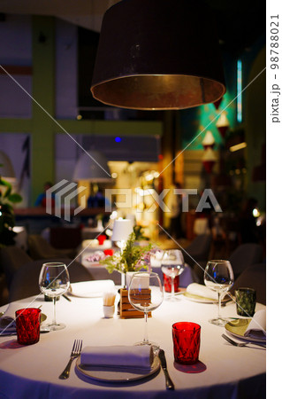 a table with a white tablecloth, glasses, crockery and decor in dark restaurant a table with a white tablecloth, glasses, crockery and decor in dark restaurant 98788021