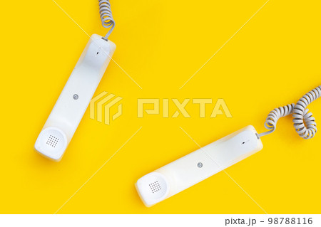 Handset of landline phones on yellow background. 98788116