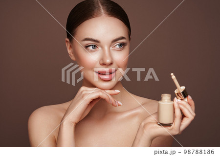 Portrait beautiful young woman with foundation bottle Portrait beautiful young woman with foundation bottle 98788186