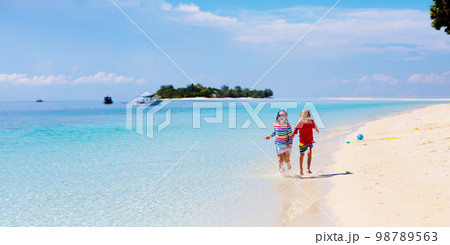 Kids play on tropical beach. Sand and water toy. 98789563