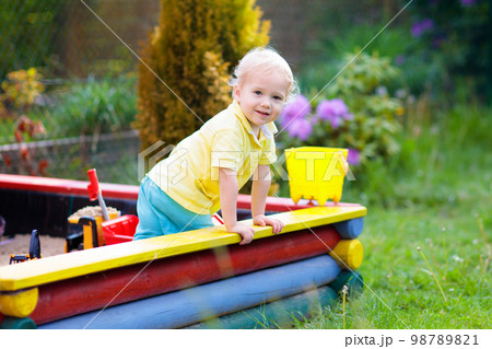 Child in sand box. Kid playing with sand. 98789821