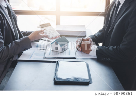 Business property,real estate and investment concepts. Real estate agent present terms of the home purchase agreement to customer,investor discussing real estate investment 98790861
