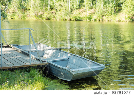 an old boat with oars on a green pond against the backdrop of a forest. an old boat with oars on a green pond against the backdrop of a forest. 98791077