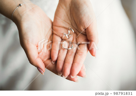 Beautiful luxury bride in elegant white dress holds wedding rings in the hands 98791831