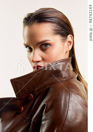 Deep look, wet hair. Beautiful young brunette girl in stylish leather jacket posing over grey studio background. Concept of beauty, fashion Deep look, wet hair. Beautiful young brunette girl in stylish leather jacket posing over grey studio background. Concept of beauty, fashion 98792164