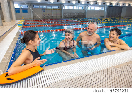 Two seniors talking to their water fitness coach after the class Two seniors talking to their water fitness coach after the class 98795051
